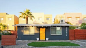 A modern two-story house with a yellow door, numbered 1113, featuring a small front yard with a lawn and a wooden planter. - Vibey 2-bedroom property with a Vintage Airstream in sunny Tempe (Tempe)