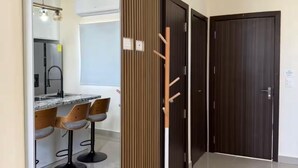 A modern kitchen with a large mirror, wooden panel wall, and a bar area with stools. - Relax, Unwind & Enjoy Punta Cana at The Grace Place (Punta Cana)