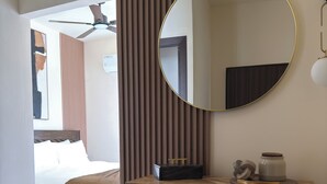 A modern bedroom with a bed, a wooden cabinet with drawers, a round mirror, and a ceiling fan. - Relax, Unwind & Enjoy Punta Cana at The Grace Place (Punta Cana)