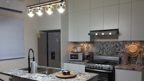 A modern kitchen with a central island, bar stools, a microwave, oven, and a gas stove. - Relax, Unwind & Enjoy Punta Cana at The Grace Place (Punta Cana)