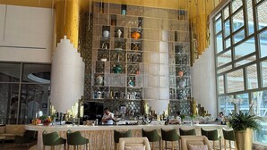 A modern bar area with a high ceiling, a bartender, and a seating area with bar stools and armchairs. - Charming Garza 5+ Diamond resort in Cancún, enjoy and relax! (Cancún)
