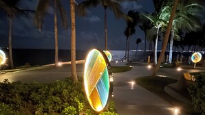 A pathway with illuminated signs, palm trees, and a view of the ocean at night. - Charming Garza 5+ Diamond resort in Cancún, enjoy and relax! (Cancún)