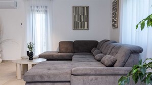 A modern living room with a sectional sofa, a small round table, and a potted plant.
