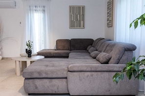 Una sala de estar moderna con un sofá seccional, una mesita redonda y una planta en maceta.