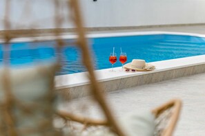 Zona de piscina con vista despejada al agua, dos vasos de bebida roja y una pajita.