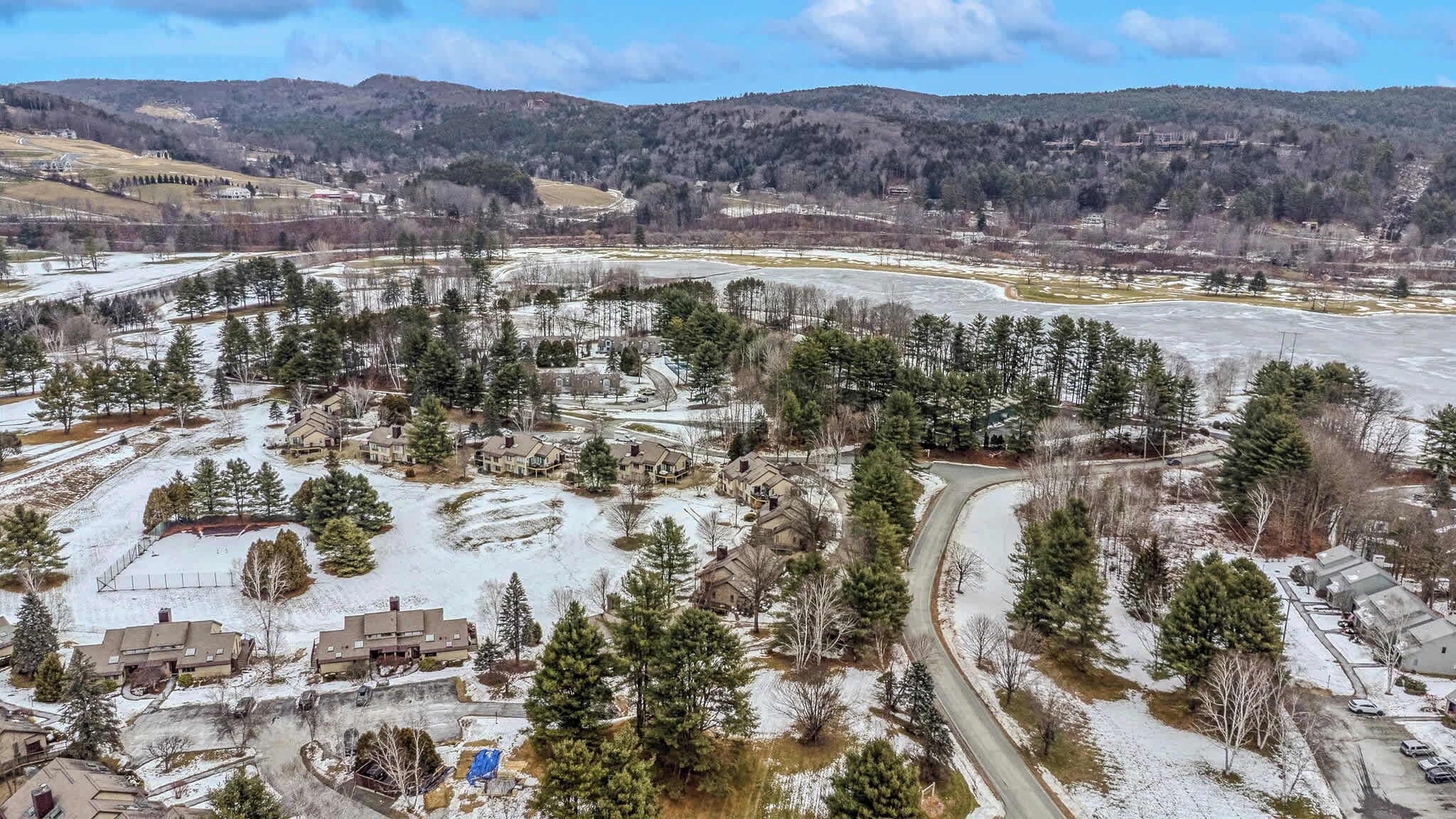 An aerial view of a residential area with houses, roads, and surrounding hills.