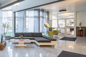 Un saló modern amb un sofà modular, una taula de centre i un finestral gran que deixa entrar llum natural.