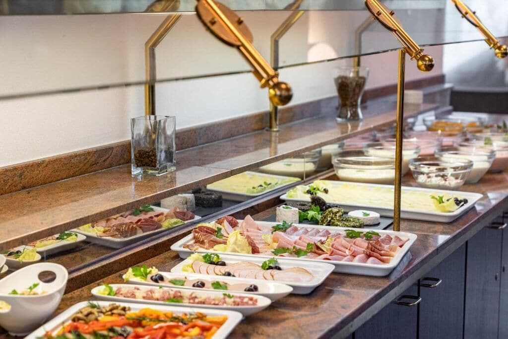 A buffet with various food items and a glass of water.