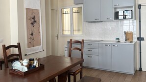 Una cocina moderna con armarios grises, un microondas y un lavamanos. Hay una mesa de comedor de madera con sillas y un banco.
