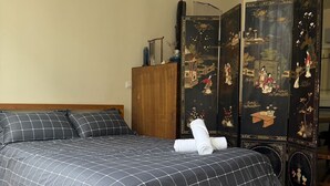 Un dormitorio con cama, armario de madera y un separador decorativo tradicional.