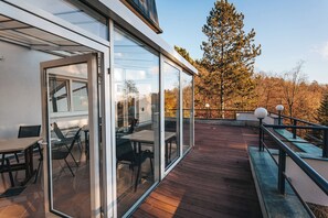 Una terraza moderna al aire libre con puertas de cristal, suelo de madera y mobiliario exterior.