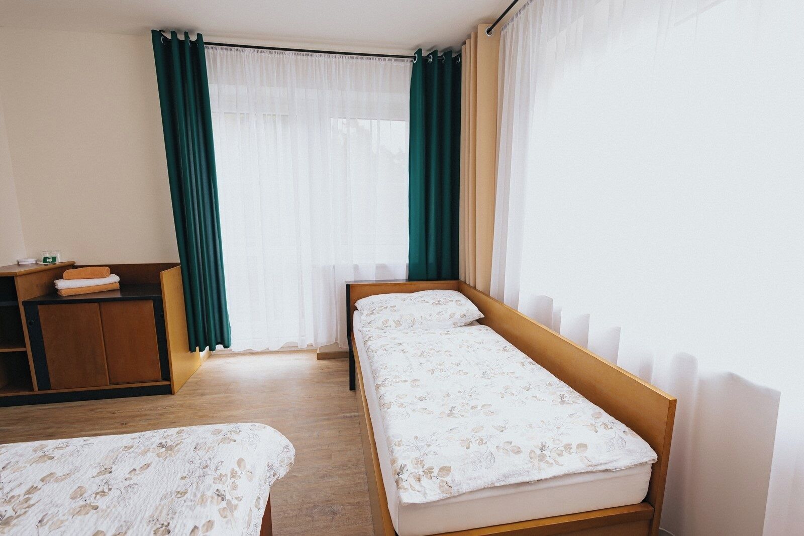 Una habitación con dos camas individuales, un escritorio de madera y una ventana con cortinas.