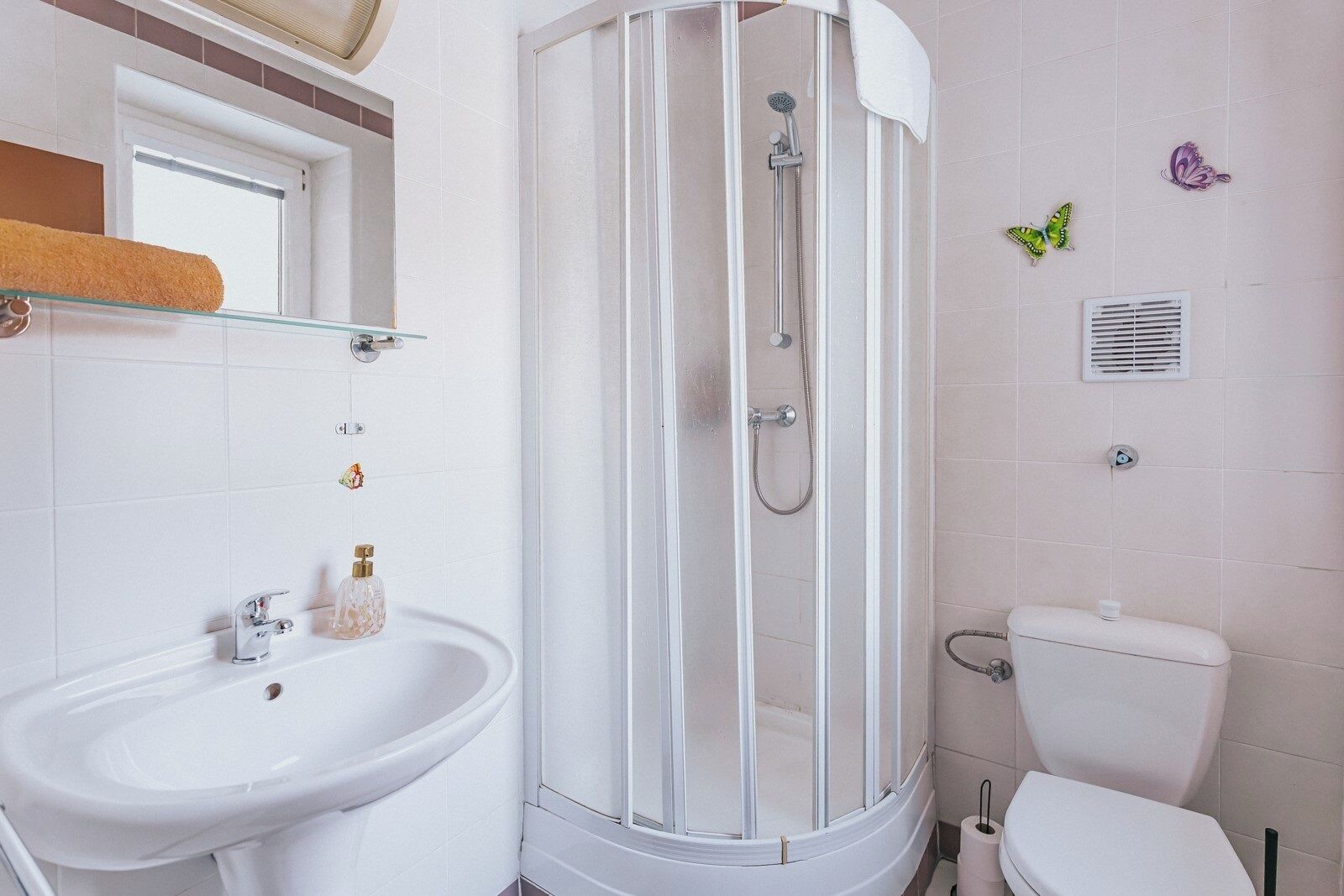 A bathroom with a shower enclosure, a sink, and a toilet.