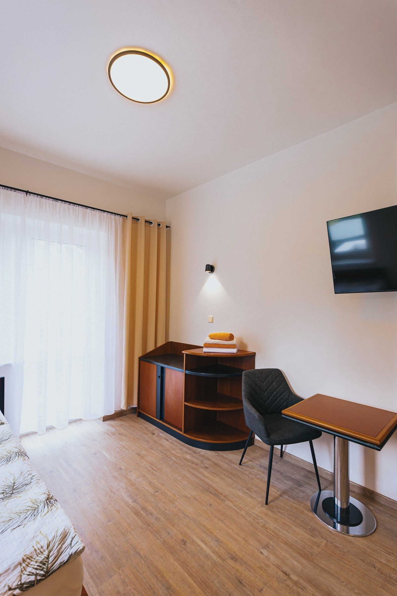 Une chambre d’hôtel équipée d’un lit, d’un bureau, d’une chaise, d’une télévision et d’une bibliothèque.