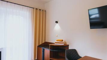 Une chambre d’hôtel équipée d’un lit, d’un bureau, d’une chaise, d’une télévision et d’une bibliothèque.
