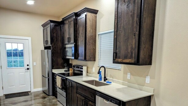 A kitchen with dark wooden cabinets, a stainless steel dishwasher, and a white countertop. - 99 per Night - New home next to KimberlyClark.662 - cleaning &taxes not included (Paris)