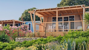 Una serie de cabañas con fachada de madera, asientos al aire libre y un jardín con diversas plantas y flores.
