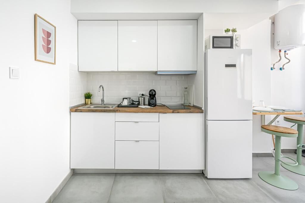 Eine moderne Küche mit weißen Schränken, einer eingebauten Mikrowelle und einem Kühlschrank.