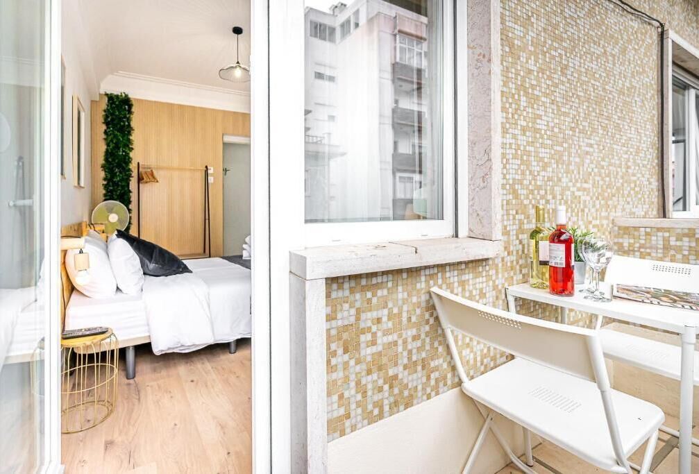 Un dormitorio moderno con una cama, mesita de noche y vistas de la ciudad a través de una ventana.