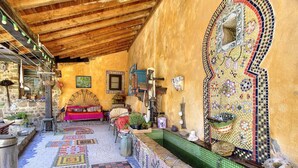 Una habitación con suelo de baldosas, techo de madera, pared con diseño y una pequeña piscina.