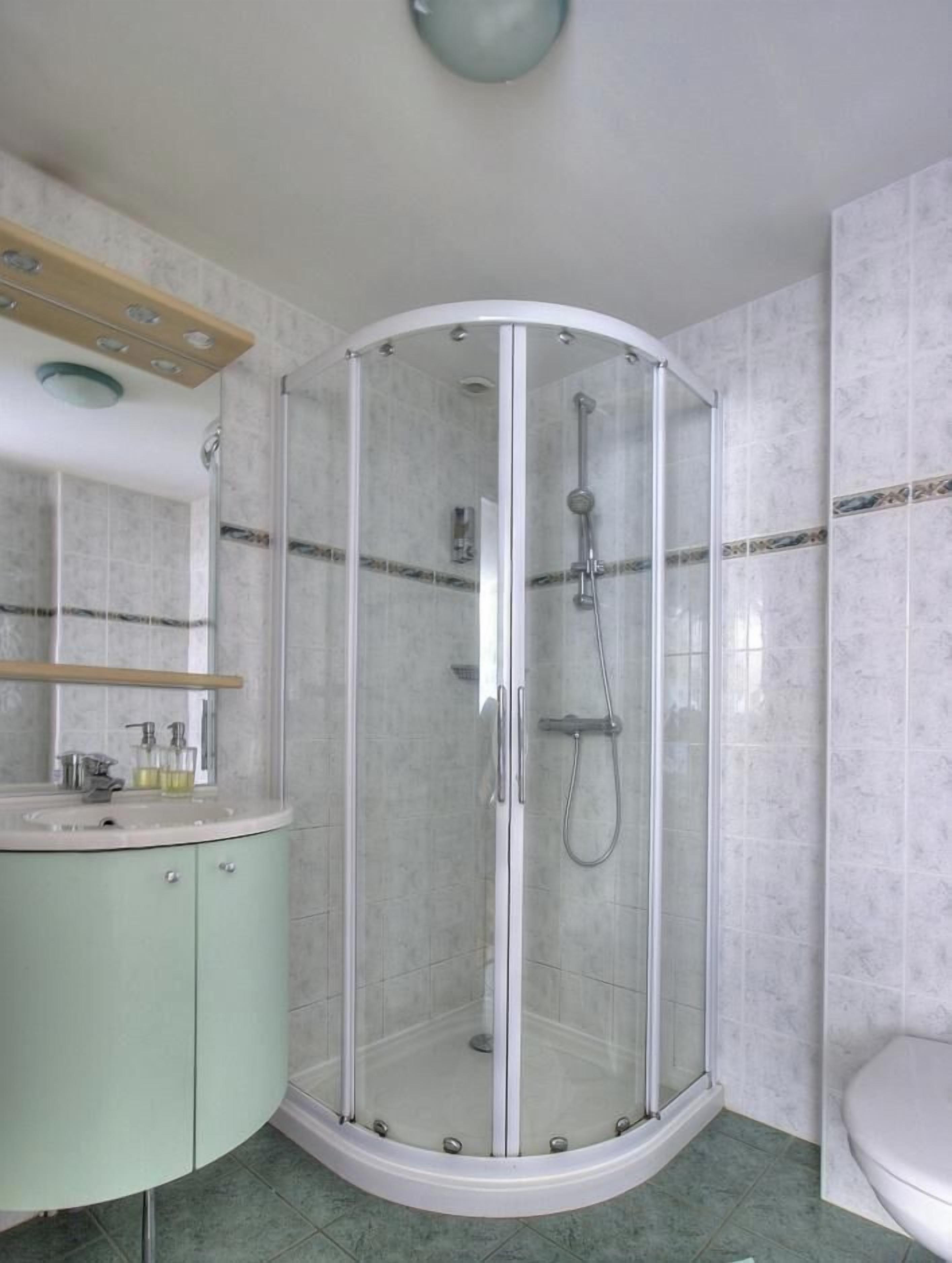 A bathroom with a glass-enclosed shower, a sink with a mirror, and a toilet.
