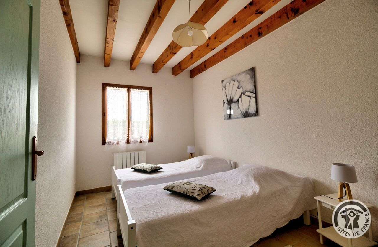 Un dormitorio con dos camas, una ventana, un radiador y un cuadro en la pared.