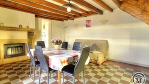 Un comedor con piso a cuadros, una mesa con sillas, una chimenea y un ventilador de techo.