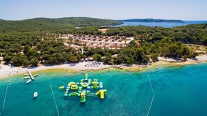 An aerial view of a coastal area with a cluster of buildings surrounded by greenery and a clear blue sea. - Nice (sta)caravan in Pula with house sea view (Pula)