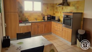 Eine kompakte Küche mit Holzschränken, einem eingebauten Ofen und einem Fenster, das für natürliches Licht sorgt.