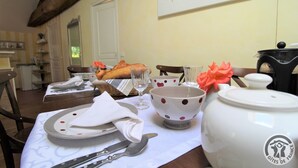 Uma mesa de jantar posta com pratos, talheres, um bule e uma tigela.
