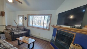 A living room with a fireplace, a television, and a sofa. - ENTIRE LAKEFRONT 10-bedroom Chateau Getaway at Whitecap Mountains Resort (Upson)
