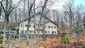 A two-story building with a sloped roof, surrounded by trees and a body of water. - ENTIRE LAKEFRONT 10-bedroom Chateau Getaway at Whitecap Mountains Resort (Upson)