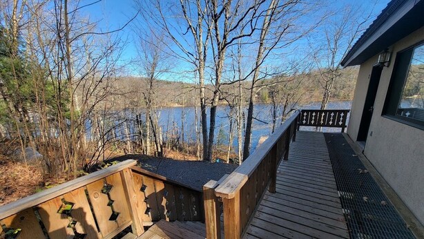 A wooden deck with a railing overlooking a body of water and trees. - ENTIRE LAKEFRONT 10-bedroom Chateau Getaway at Whitecap Mountains Resort (Upson)