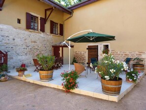 A courtyard with stone walls, wooden furniture, and potted plants. - Le Clos des Rues - ARNAS (ARNAS)