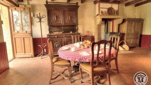 Un coin repas comprenant une table ronde, des chaises, un buffet et une cheminée.