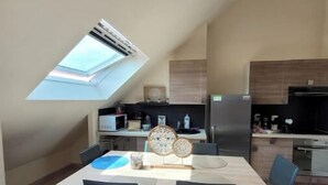 Una cocina moderna con tragaluces, un comedor con mesa y sillas, y una isla de cocina.