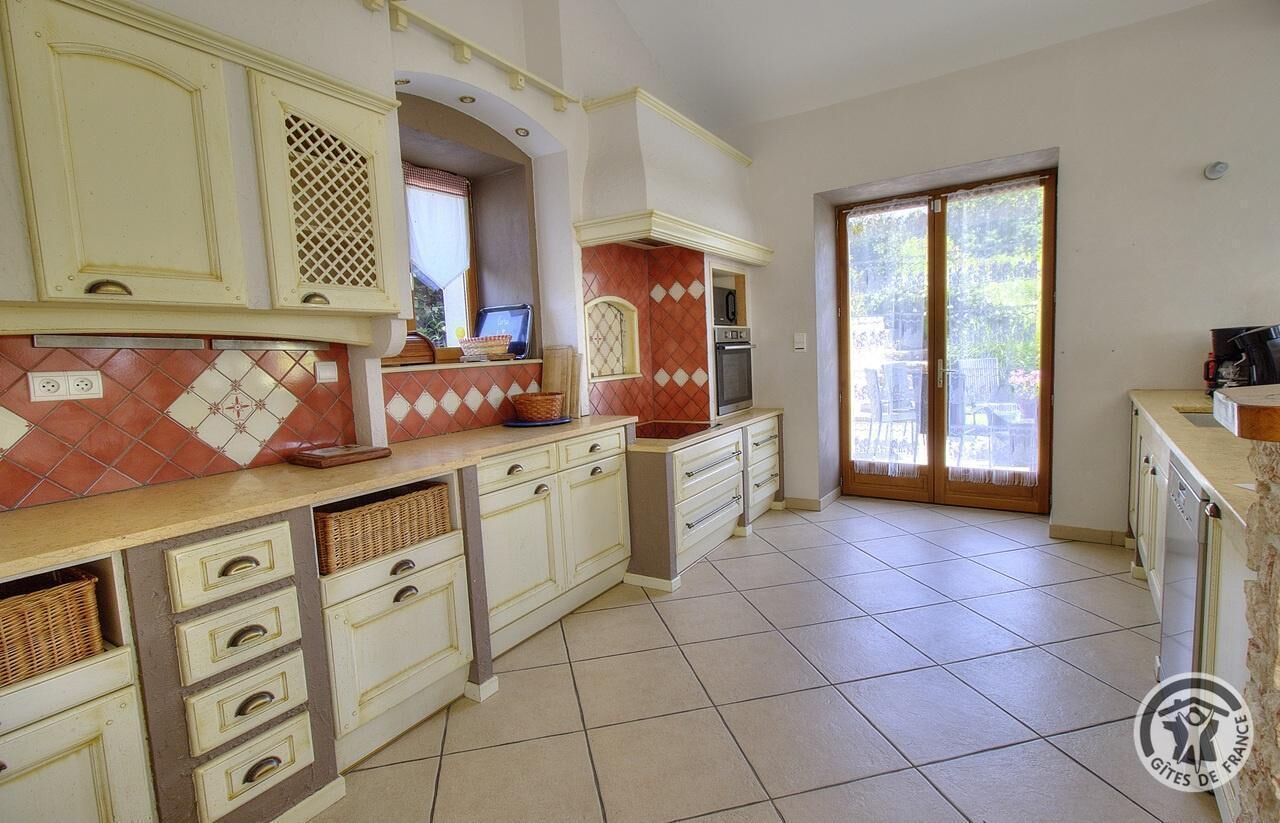 A kitchen with a tiled floor, a built-in oven, and a large window.