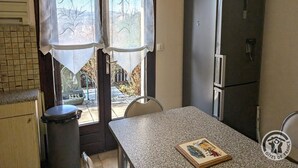 A compact kitchen with a refrigerator, a window with a view, and a small dining table. - Les Griottes - SAIN-BEL (SAIN-BEL)