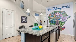Eine Küche mit Granit Arbeitsplatte, einer Kochinsel und einem Wandbild von Disney World.