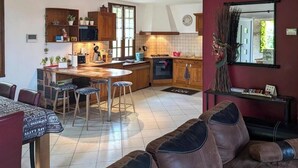 A kitchen with wooden cabinets, a dining area with a table and chairs, and a living room with a sofa. - Citybreak Le Planier (SAINT PRIEST)