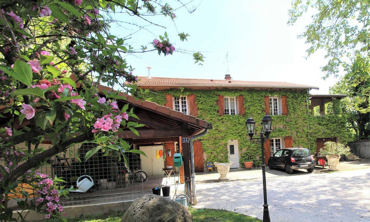 A two-story building with a red-tiled roof, ivy-covered walls, and a car parked in the driveway.