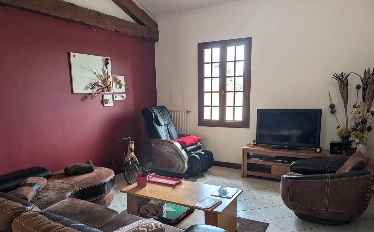 A living room with a sofa, a chair, a coffee table, a TV, and a window.