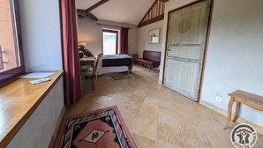 Een kamer met een bed, een bureau, een stoel, een raam met gordijnen en een deur.