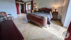 Een slaapkamer met een groot bed, een houten dressoir en een stoel.