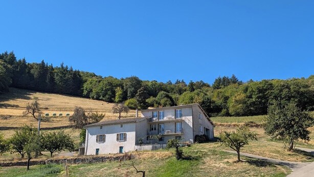A two-story house with a balcony, surrounded by a rural landscape with trees and a clear sky. - Gîte de la Panoncelière 2 (RONTALON)