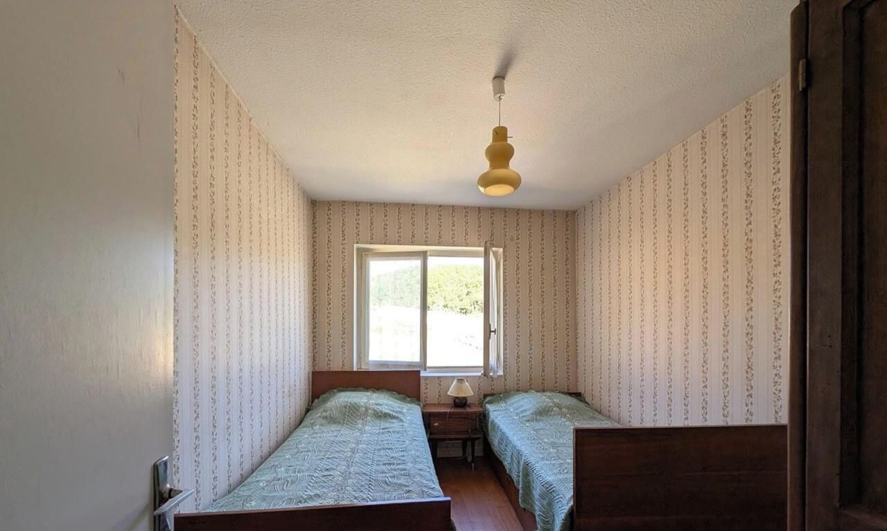 Une chambre avec deux lits, une fenêtre et un luminaire suspendu.