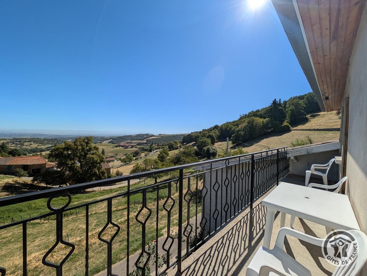 Een balkon met uitzicht op een landelijk landschap, een tafel met stoelen en een leuning.