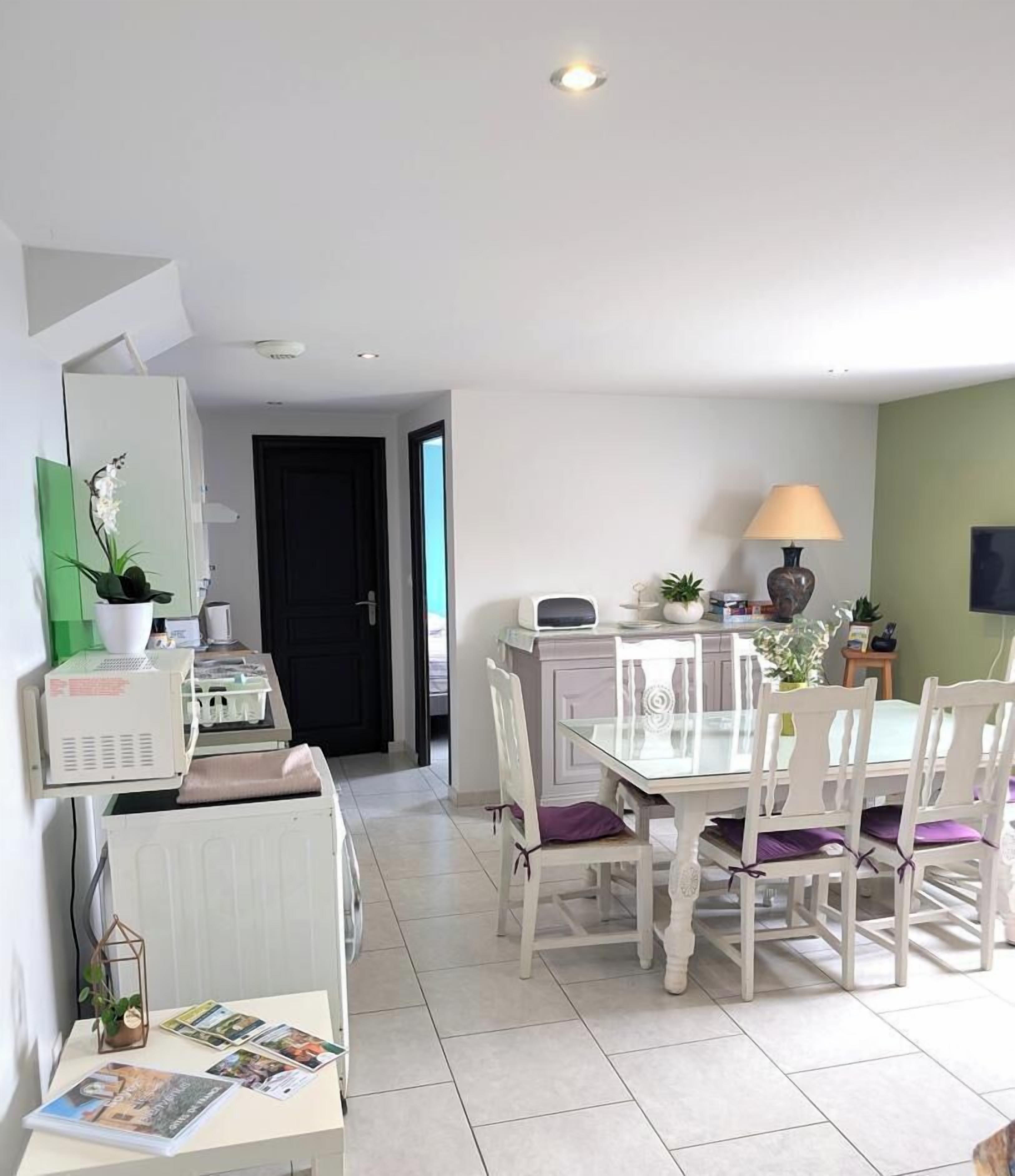 Un coin repas avec une table et des chaises, une lampe et un téléviseur fixé au mur.