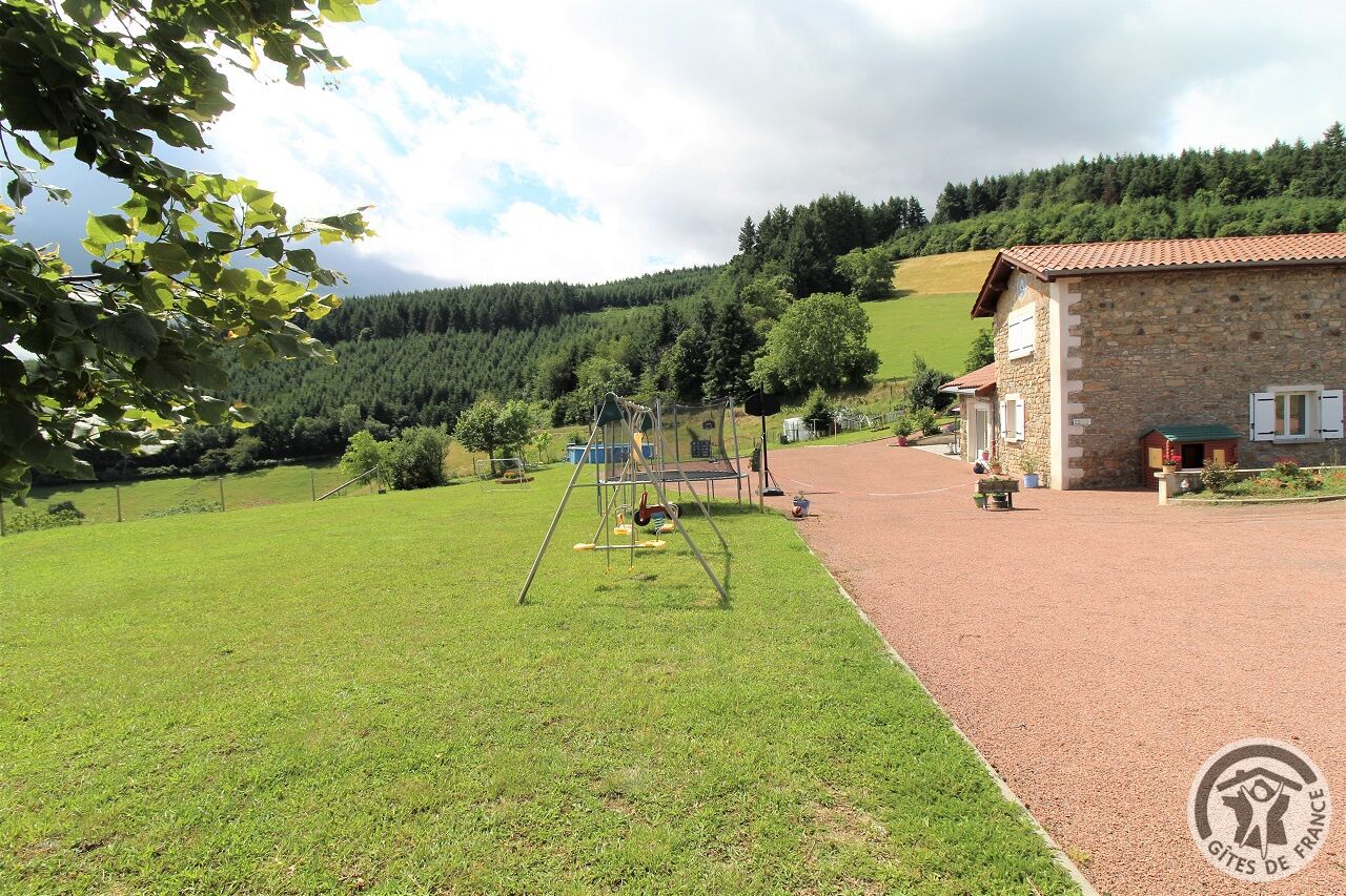 Ein ländliches Anwesen mit einem Steinhaus, einem Spielplatz und einem gepflegten Rasen.