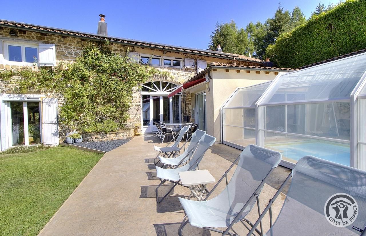 A house with a glass greenhouse, outdoor seating area, and a swimming pool.